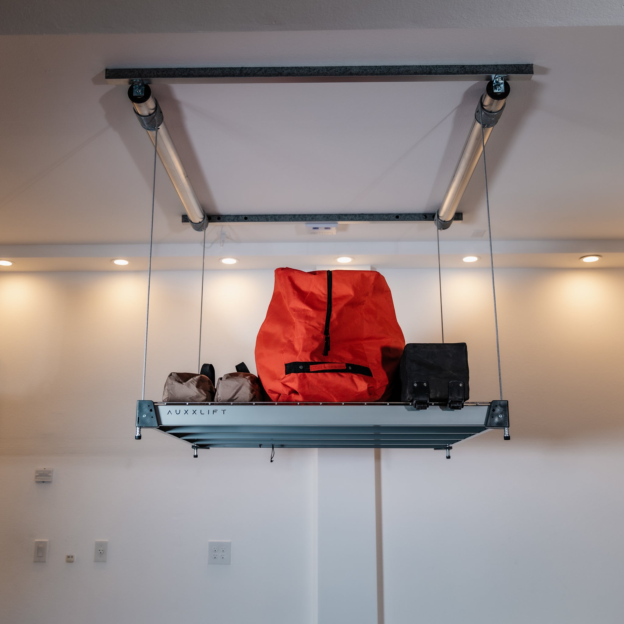 Auxx-Lift Motorized Garage Ceiling Storage Lift lowered with orange bag in finished garage